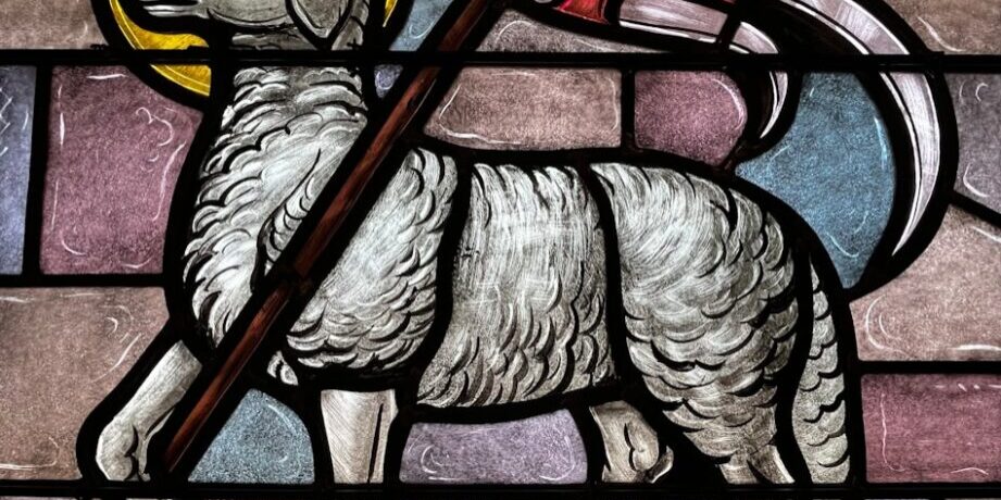 a stained glass window with a sheep holding a flag