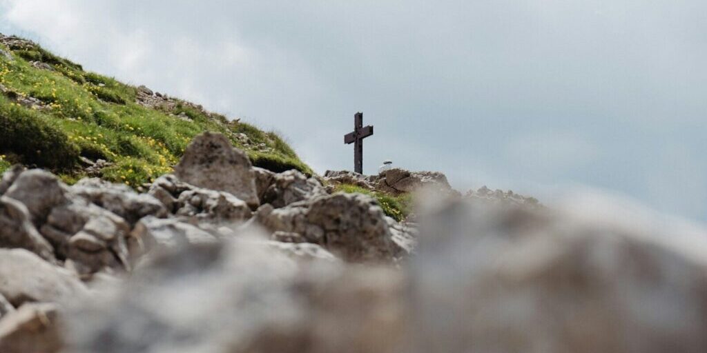 black cross on gray rocks under white sky during daytime